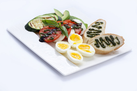 breakfast toast with pesto sauce , eggs, and tomatoes with mozzarella cheese , fried zucchini , and not a lot of avocado.の写真素材