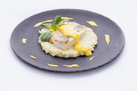 roasted fillet of cod on a bed of risotto flavored sauce and carnationsの写真素材