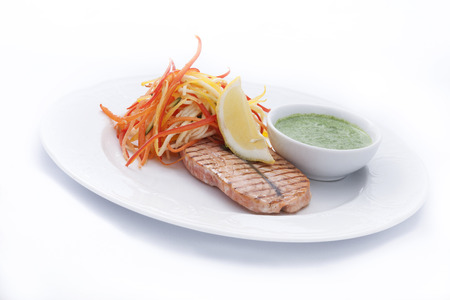 Grilled salmon with grated vegetables , sauce and lemonの写真素材