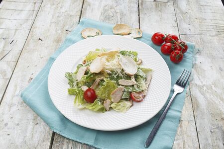 Caesar salad with chicken and greens on wooden tableの写真素材