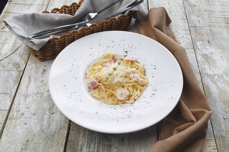 Pasta Carbonara. Spaghetti with bacon and parmesan cheese. Pasta Carbonara on white plate with parmesan on dark backgroundの写真素材