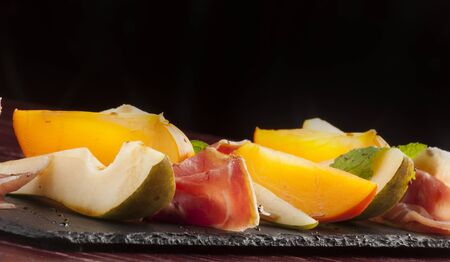Appetizer of Parma ham and vegetables on wooden panel, selective focusの写真素材