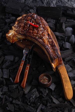 grilled tomahawk steak on wooden plate ready for eat. On background coalの写真素材