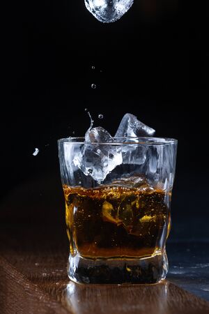 Glass with whiskey and ice on a bar counterの写真素材