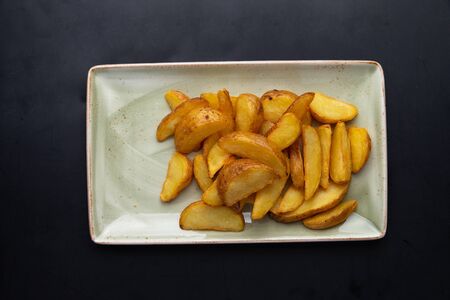 fried potato wedges in a plate on a dark backgroundの写真素材