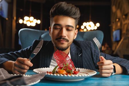 A young guy sits at a table and is going to eatの写真素材