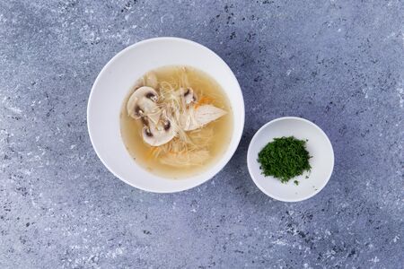 Noodle soup with mushrooms in a plate on a gray backgroundの写真素材