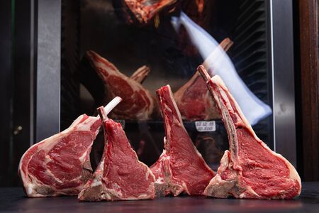 various raw steaks on a background of dry aging cabinetの写真素材