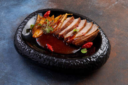 Roasted duck and caramelized pear in a dark plateの写真素材