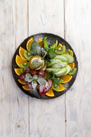 Assorted fruits in a plate. On a light backgroundの写真素材