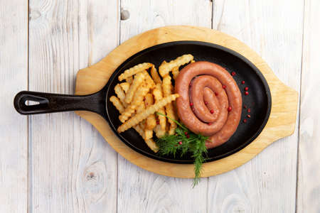 Traditional sausage and fries in a skillet. On a light background. Selective focusの写真素材