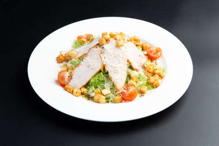 salad with chicken and croutons. Caesar salad. In a plate on a dark backgroundの写真素材