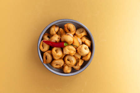 Fried dumplings and chili peppers in a plate on a yellow backgroundの写真素材