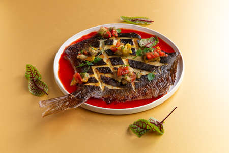 fried flounder in a plate on a yellow background. Selective focus