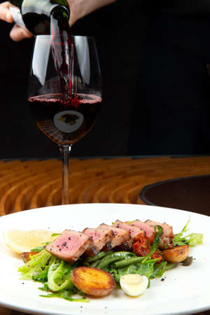 fried tuna on a pad of green beans and young potatoes on a plate.の写真素材