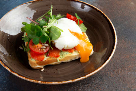 sandwich with poached egg, salmon and tomatoes in a plate. selective focus