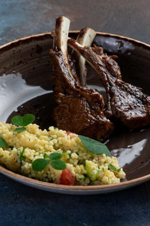 Lamb rack in a plate on a dark background. Selective focus