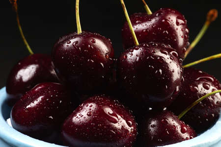Sweet cherries in a blue cup on a dark background. Selective focus