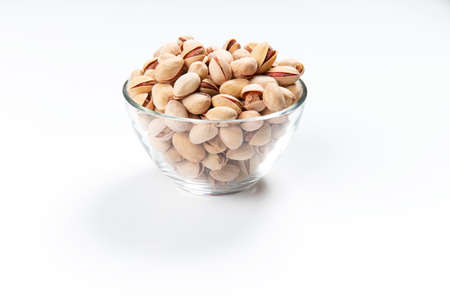 Pistachios in a glass cup on a white background. Close-up. Selective focus.