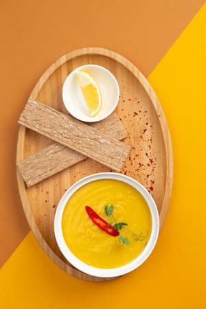 Pumpkin cream soup. In a plate on a colored background. Selective focus.の写真素材