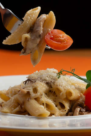 Pasta with cheese and tomatoes planted on a fork. Selective focus.の写真素材