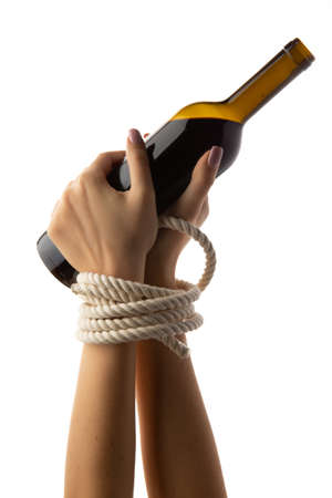 Tied female hands hold a bottle of wine isolated on white background.の写真素材