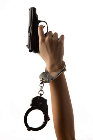 Hand with handcuffs and a pistol. isolated on white background.の写真素材