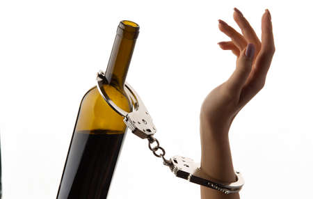 Hands chained to a bottle of alcohol. isolated on white background.の写真素材