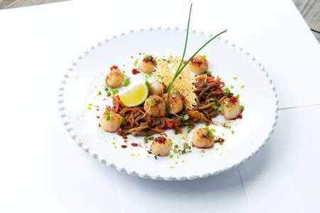 Fried scallops with vegetables in a plate. Isolated on white background. Selective focusの写真素材