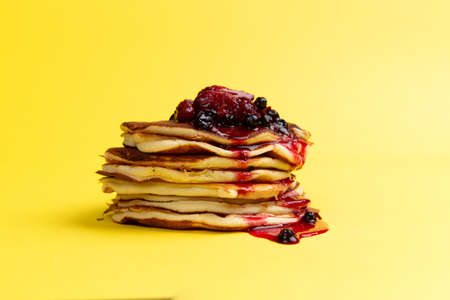 Stack of pancakes with berry jam on a yellow background.の写真素材