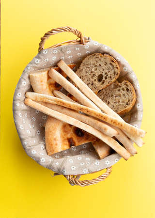 Basket with various types of bread. On a yellow background. Selective focus.