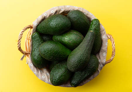 Basket with avocado on a yellow background.の写真素材