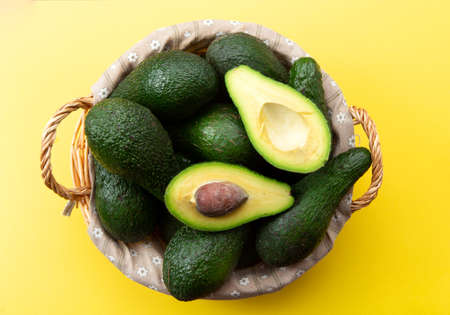 Basket with avocado on a yellow background.の写真素材
