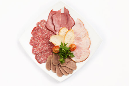 Slicing various types of meat and sausages in a plate. Isolated on white background.