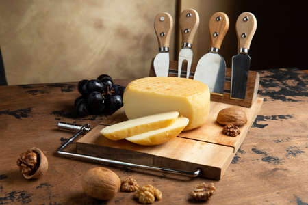 A small head of cheese and a cut piece. On a wooden table. Selective focus.の写真素材