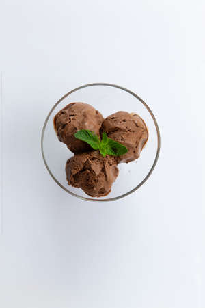 Three scoops of Chocolate ice cream in a glass bowl. view from above. On a white background....