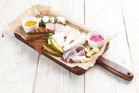 Assorted snacks on the board. Salo, pickles, rye bread. On a light background. selective focus.の写真素材