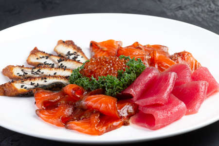Assorted fish cut into slices. Salmon, eel, tuna, trout. Decorated with red caviar. selective focus.