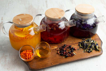 Various fruit teas in teapots on a wooden table. selective focus.の写真素材