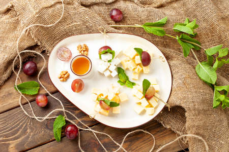 Assorted cheeses in a plate. On a wooden table.の写真素材