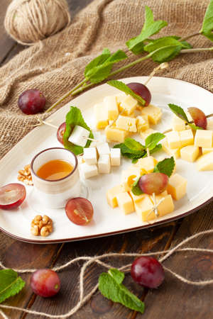 Assorted cheeses in a plate. On a wooden table.の写真素材