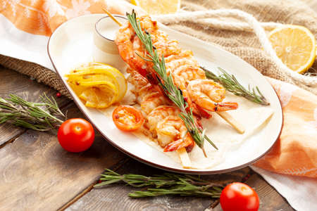 Fried shrimp on a skewer in a plate. On a wooden table.の写真素材