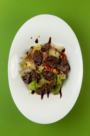 Salad with fried liver in a plate on a green background. selective focus.の写真素材