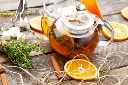 Tea with thyme and orange tea in a transparent teapot on a wooden table. selective focus.の写真素材