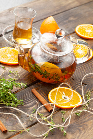 Tea with thyme and orange tea in a transparent teapot on a wooden table. selective focus.の写真素材