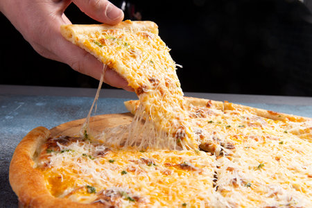 The hand takes a piece of pizza with cheese. selective focus.の写真素材