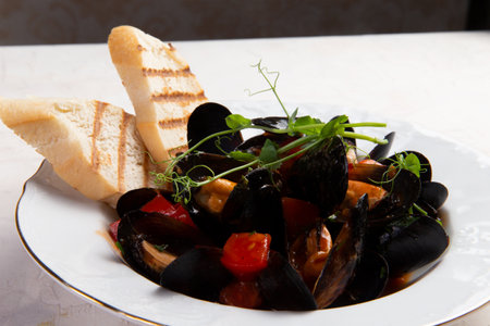 Cooked mussels and toasted bread in a plate. On a light background. selective focus.の写真素材