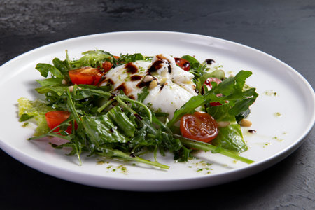 Salad with arugula, tomato and burrata cheese on a dark background. Selective focus.