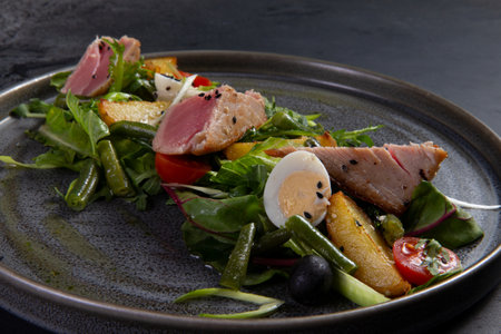Salad with pieces of fried tuna on a dark background.の写真素材