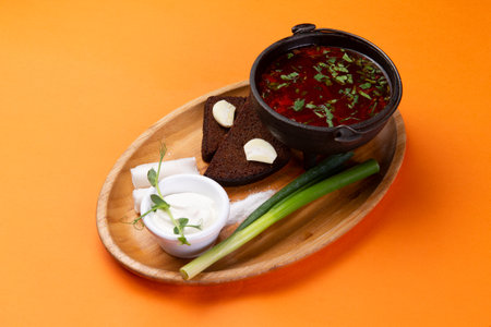 Traditional polish soup borscht with sour cream and bread on orange backgroundの写真素材